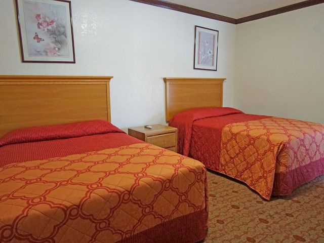 A standard hotel room with two beds, a nightstand, and artwork on the walls.
