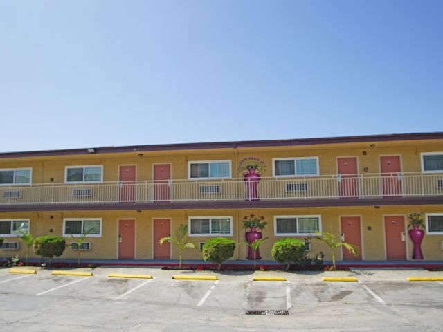 A two-story building with a yellow facade, red doors, and a balcony.