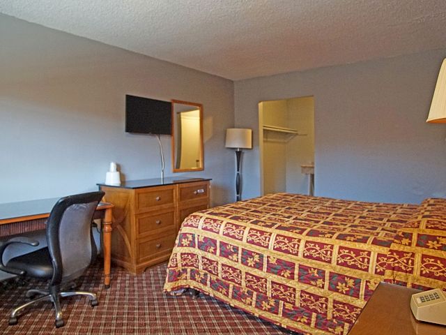 A hotel room with a bed, desk, and TV.