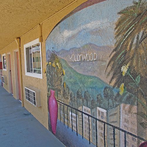 A long corridor outside a building with a mural depicting the Hollywood hills and palm trees on the wall.