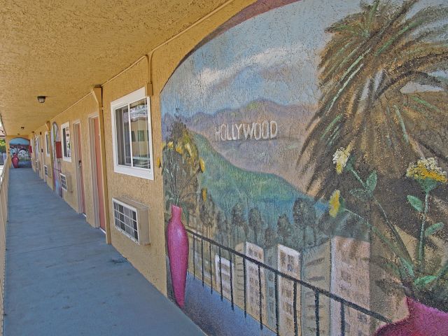 A mural on the exterior wall of a building with a balcony.