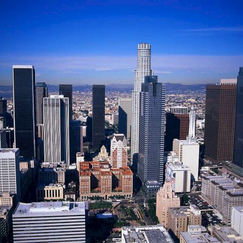 This image depicts a city skyline with numerous tall buildings, clear blue sky, and a combination of modern and historic architecture ending the sentence.