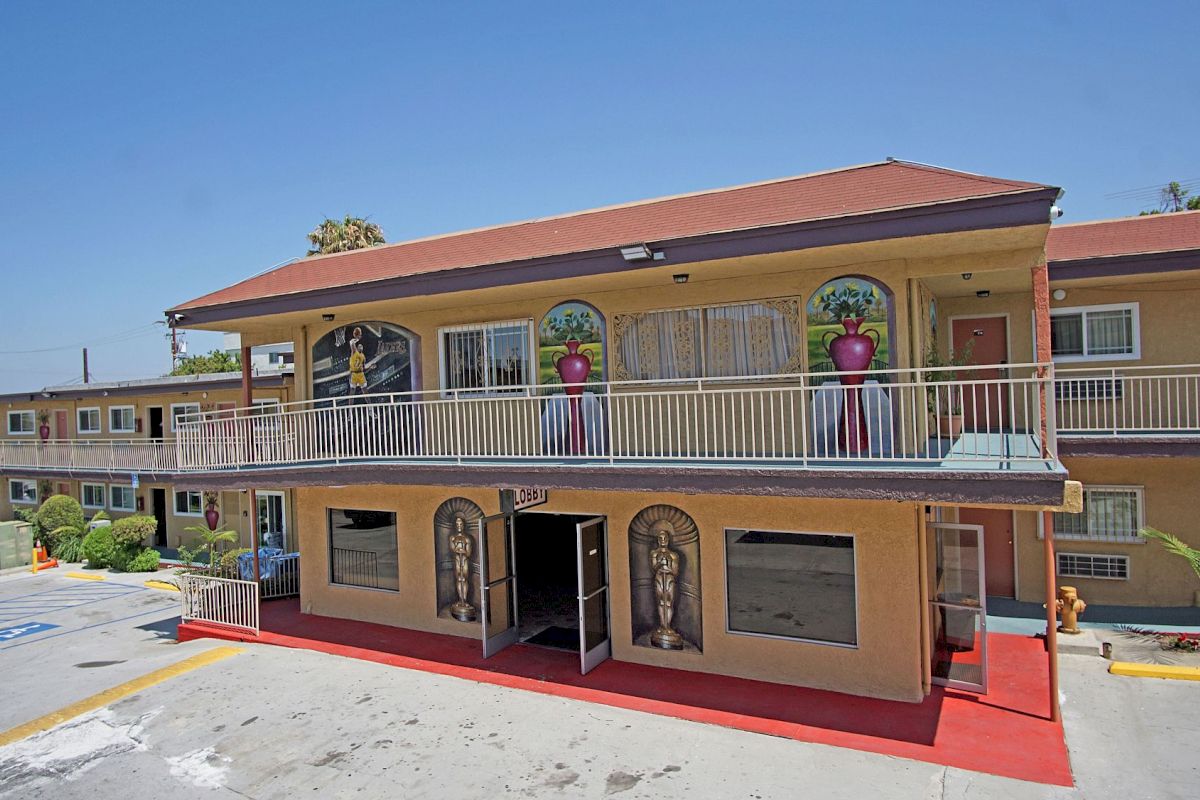 A two-story motel with a balcony and red roof under a clear blue sky