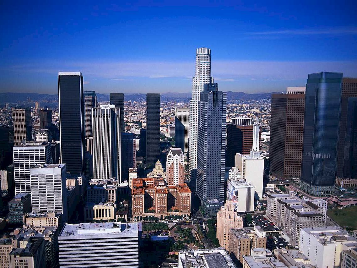 Aerial view of a cityscape with skyscrapers and a blue sky.