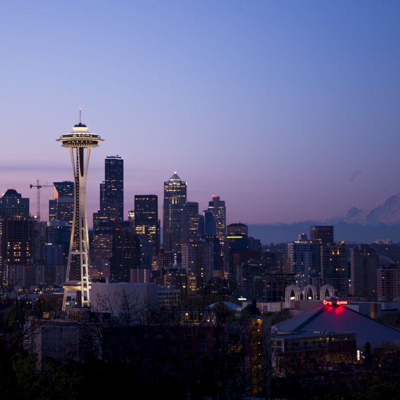 This image shows the Seattle skyline during twilight with the Space Needle prominently in the foreground and Mount Rainier visible in the background, ending the sentence.