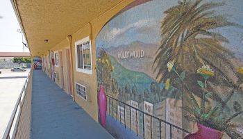 A motel exterior displays a colorful mural featuring a scenic view with 