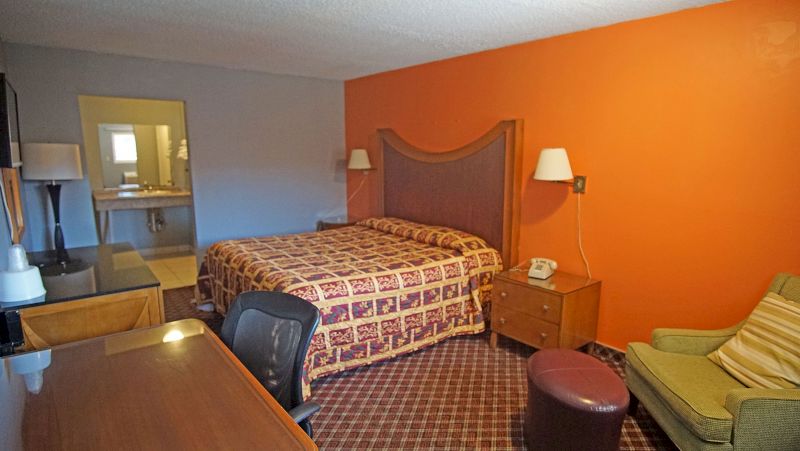A wide view of a hotel room with a bed, desk, chair, and sofa.