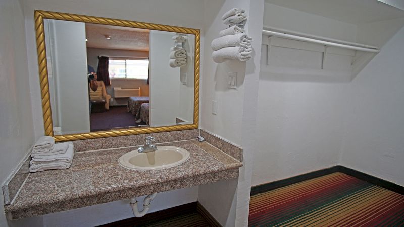 A bathroom counter with a gold-framed mirror, granite countertop, and stacked towels.